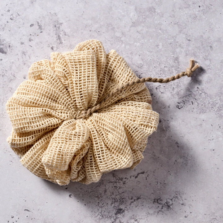 Beige mesh scrubber on a gray textured surface