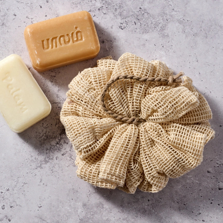 Natural sponge and two bars of soap on a gray surface