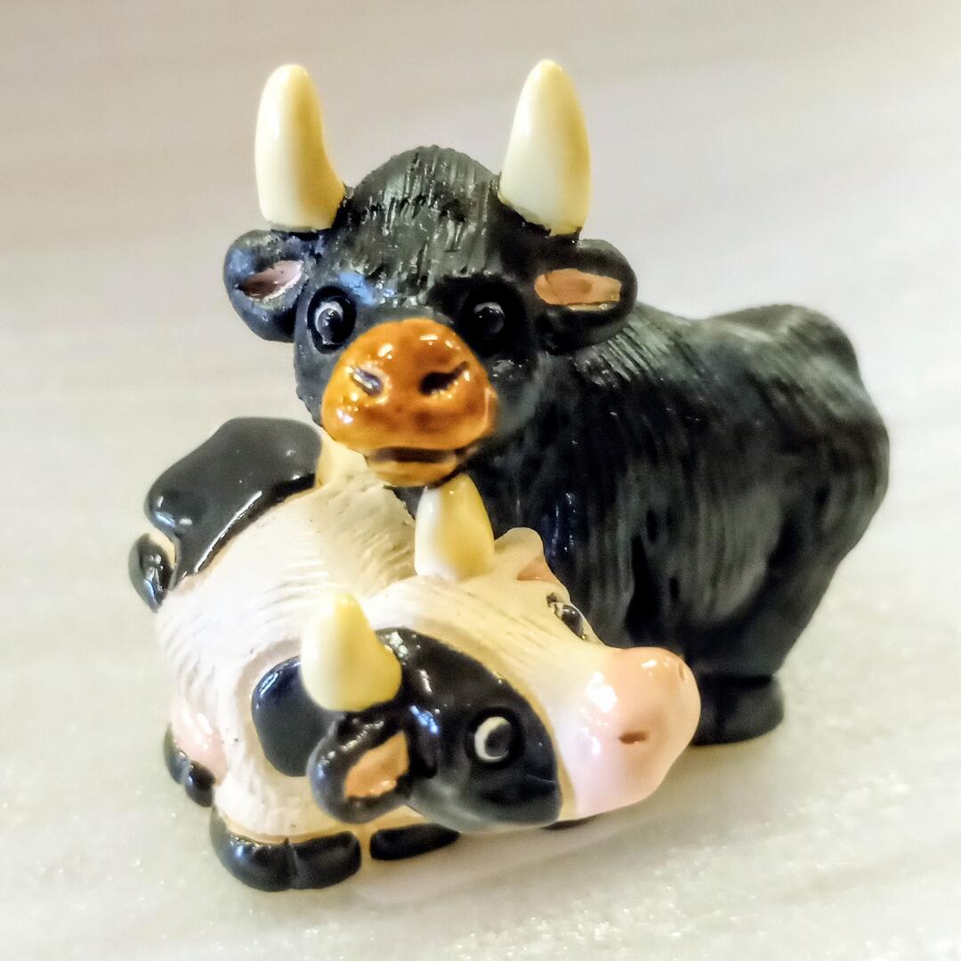 Two ceramic cow figurines with horns on a beige background. 