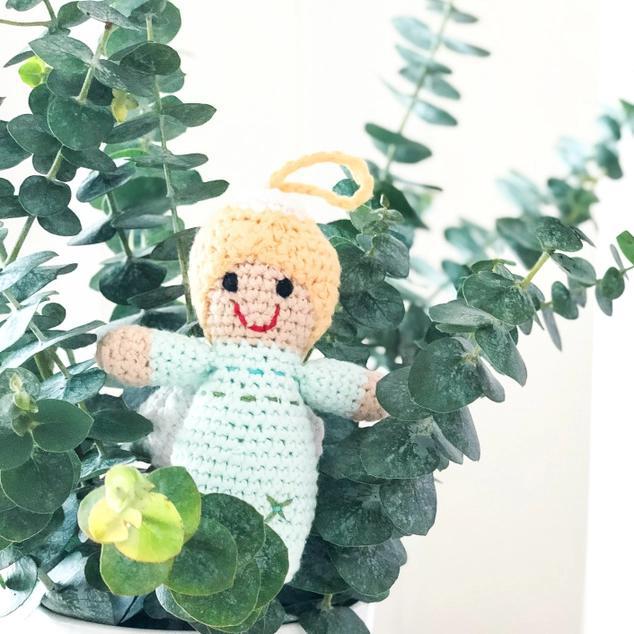 Crocheted angel toy with a halo surrounded by green leaves
