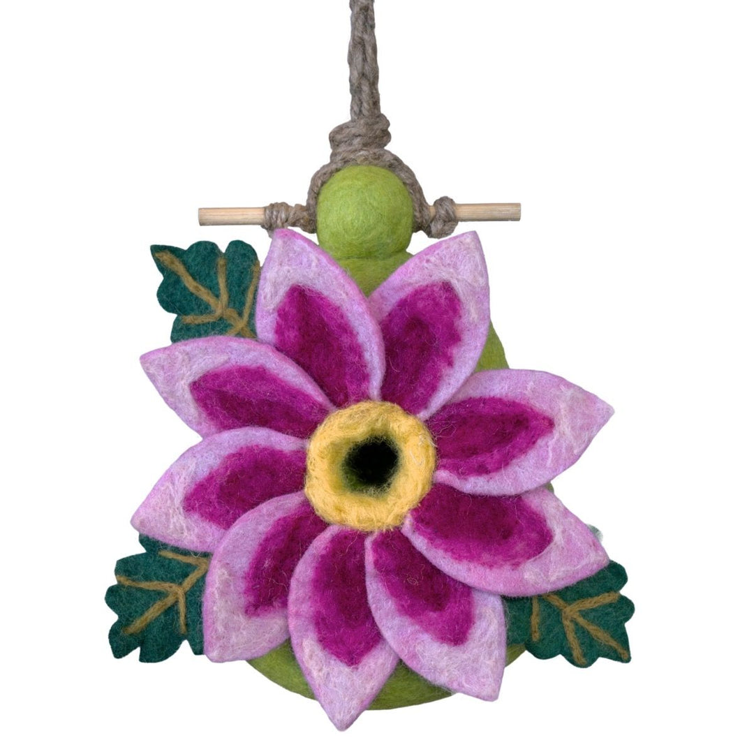 Felted flower ornament with pink petals and green leaves on a white background