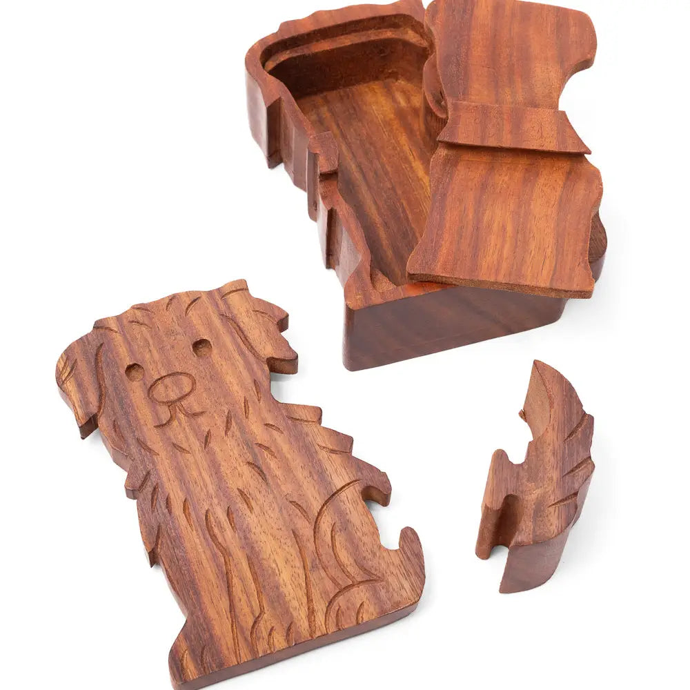 A carved wooden dog-shaped box with its lid and small accessory piece shown on a plain white background.