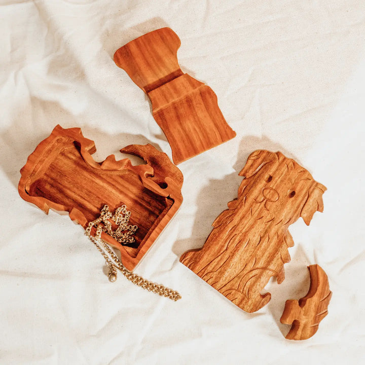 A carved wooden dog-shaped puzzle boxon a plain white background, showcasing natural wood grain and interlocking puzzle cutlines.