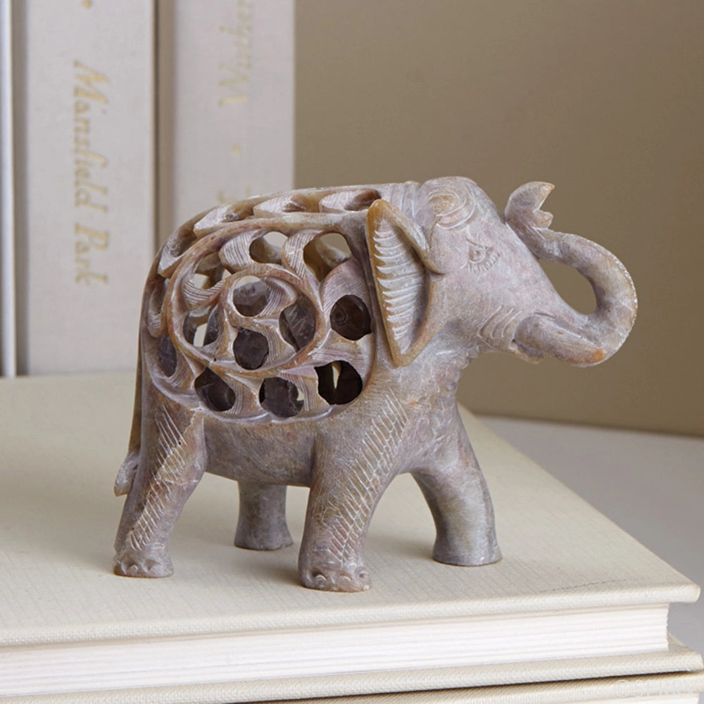 Decorative elephant sculpture on a stack of books with a neutral background