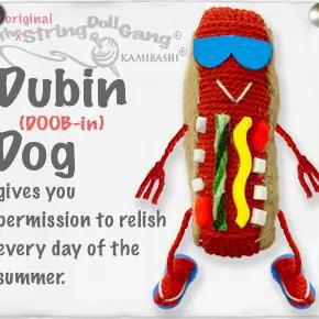 Handmade string doll keychain resembling a hot dog with sunglasses and flip flops. The string doll has a nametag and key ring attached. 