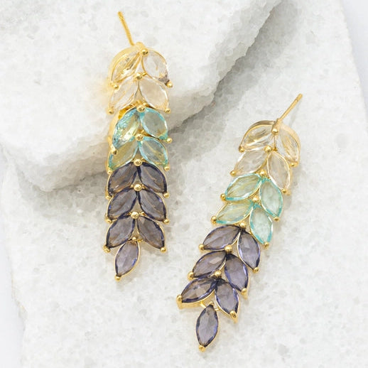 Pair of earrings with leaf-shaped gemstones on a textured white surface