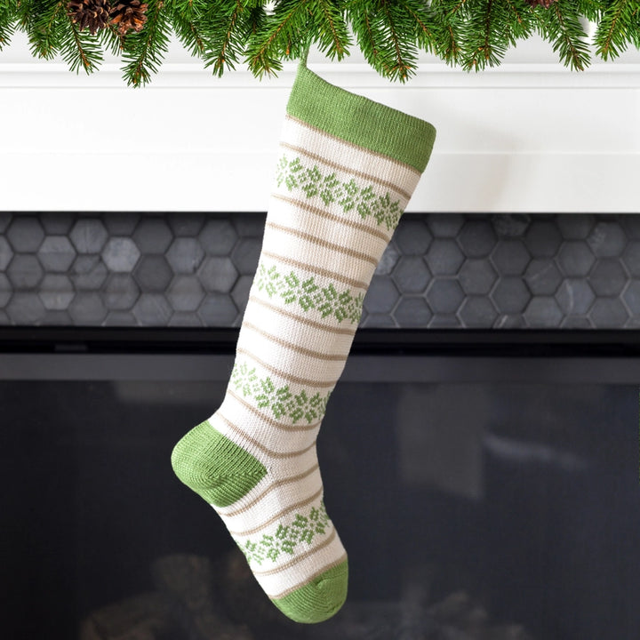 Green and beige striped sock with floral patterns hanging under a Christmas tree.
