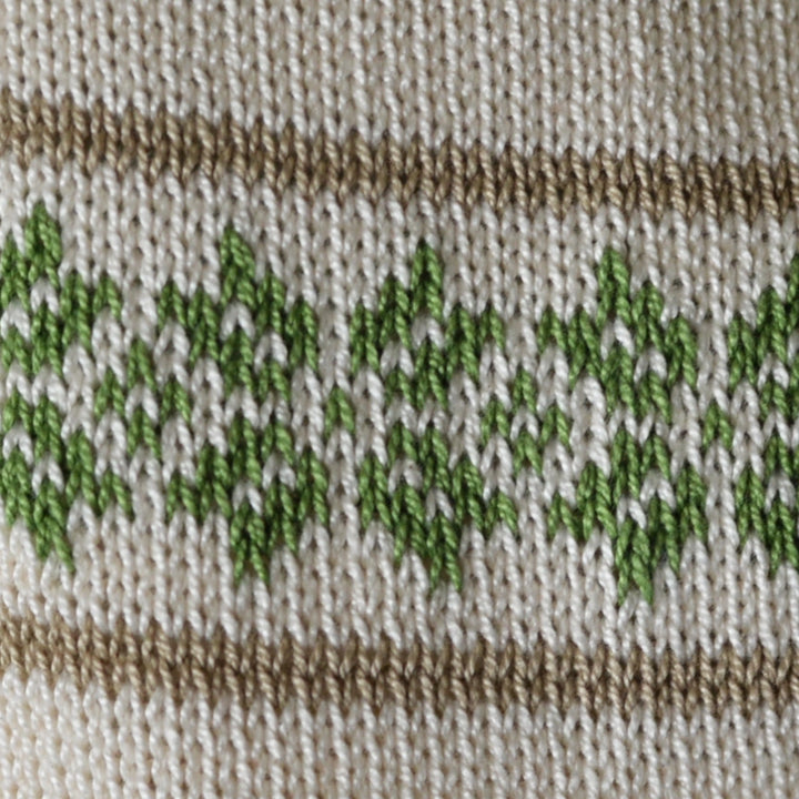 Close-up of knitted fabric with green leaf pattern on a beige background