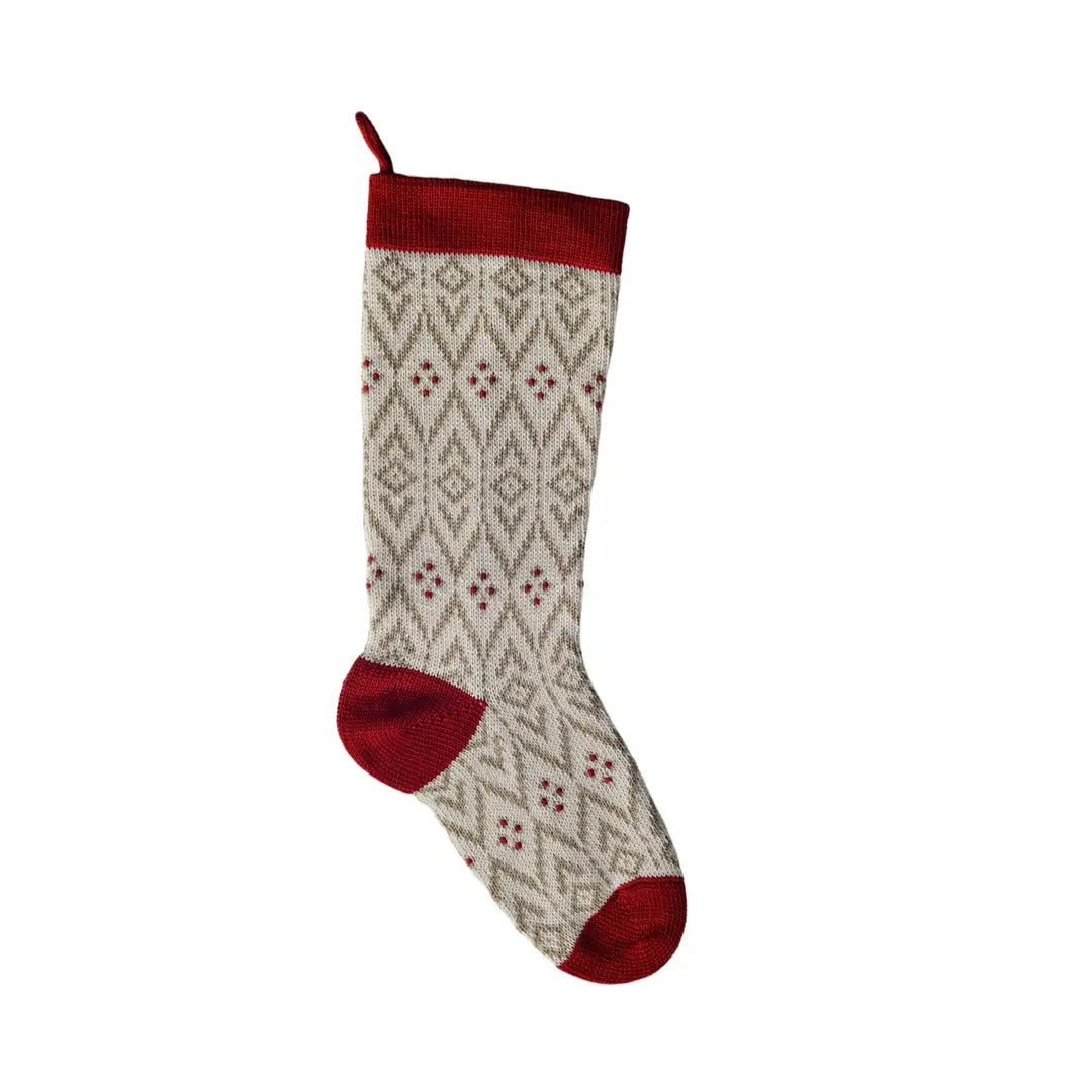 A single knit Christmas stocking with a red cuff, red heel, and red toe, featuring a beige and red geometric diamond pattern on a white background.