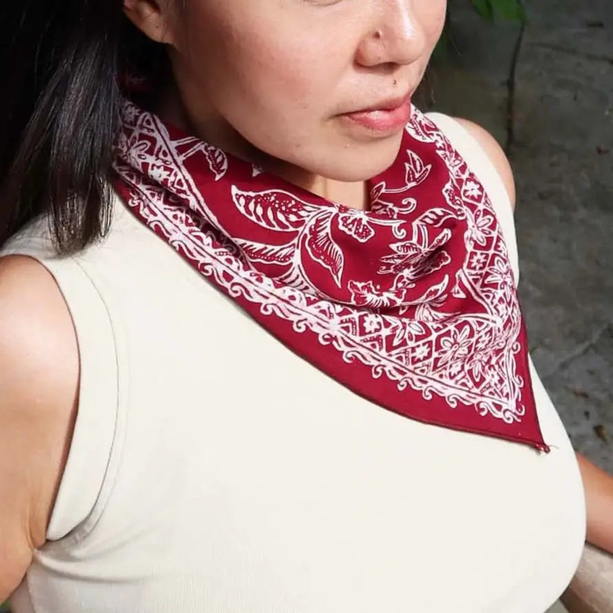 Person wearing a red bandana with white patterns on a neutral background