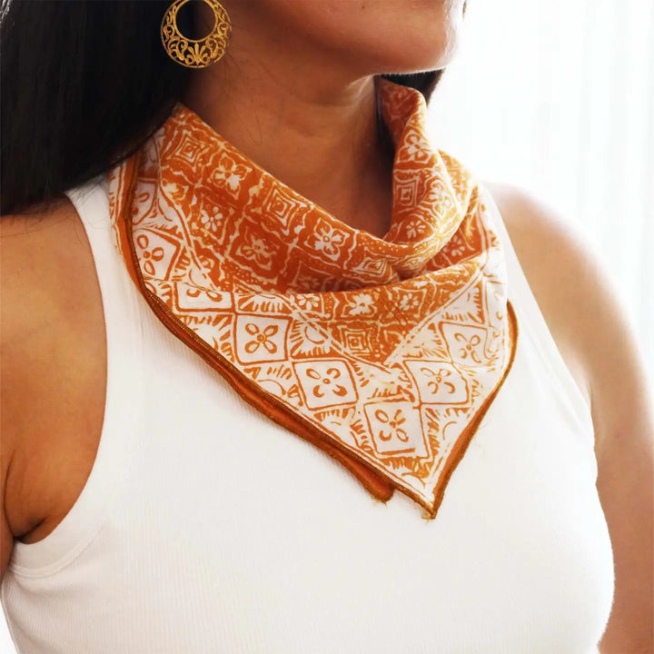 Person wearing a patterned orange bandana on a white background