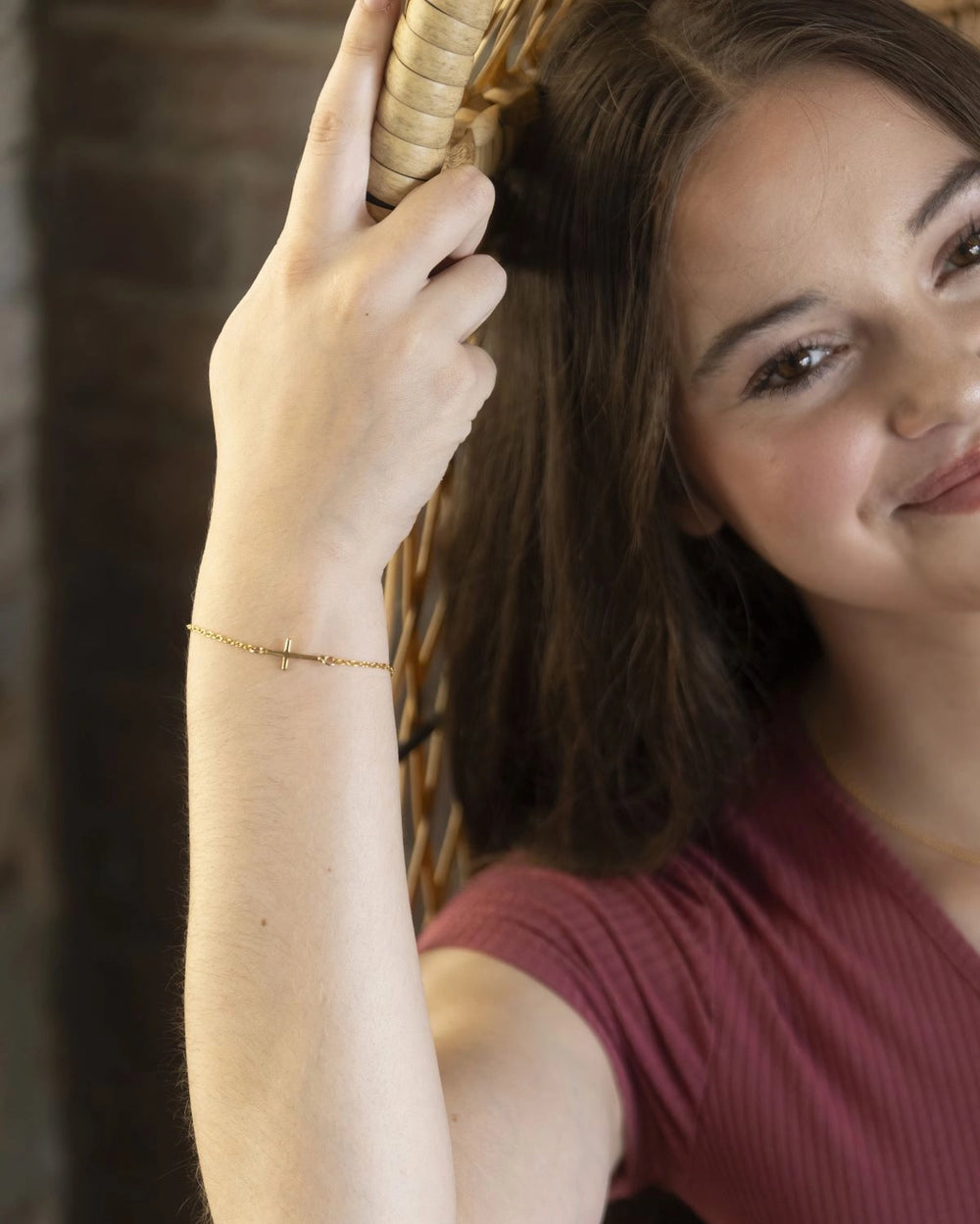 Woman wearing gold cross bracelet. 