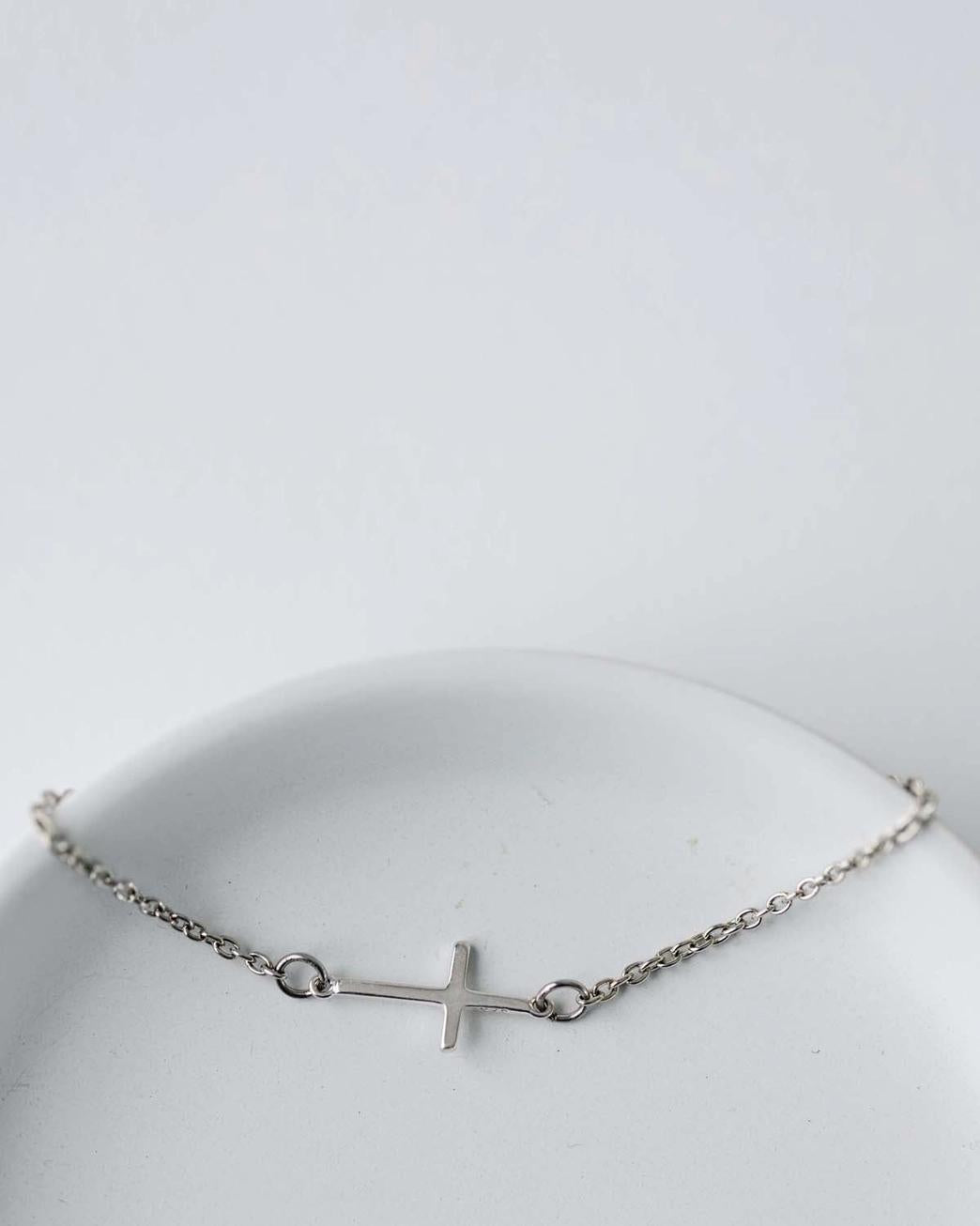 Silver bracelet with a cross on a white background