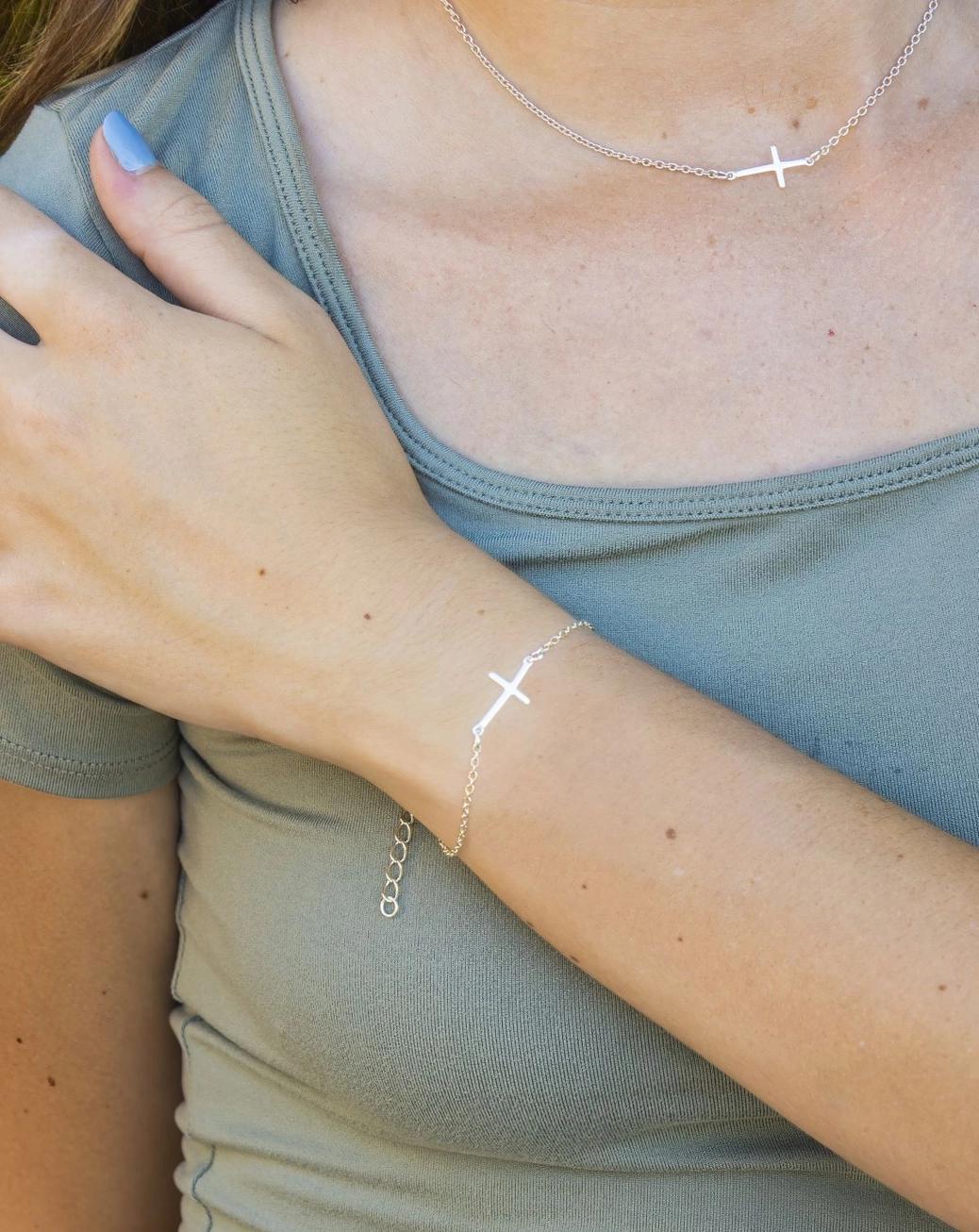 Silver cross bracelet on a wrist.