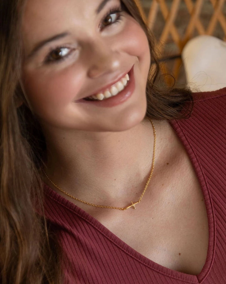 Woman wearing a gold necklace with a cross