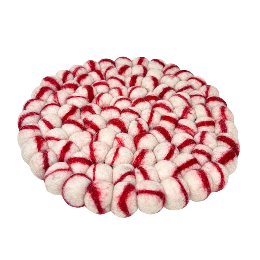 Round woven trivet with red and white pattern on a white background
