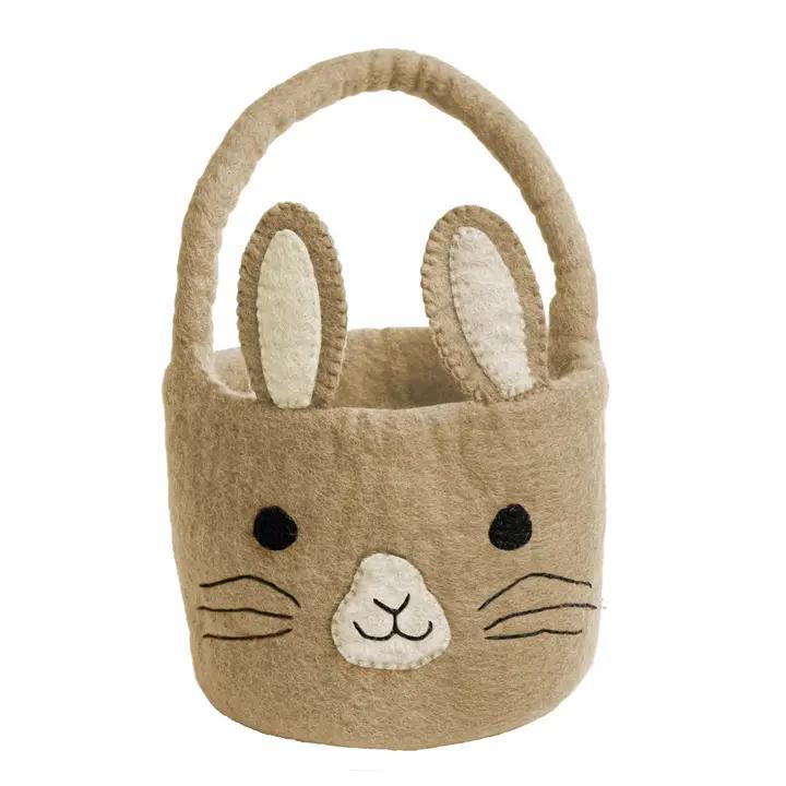 A beige felt Easter basket designed to look like a bunny with a handle, ears, and a face embroidered on the front.
