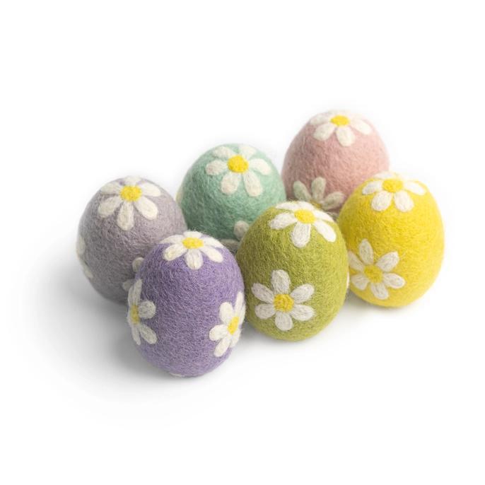 A collection of colorful felt floral Easter eggs with embroidered daisies on them, arranged on a white surface.