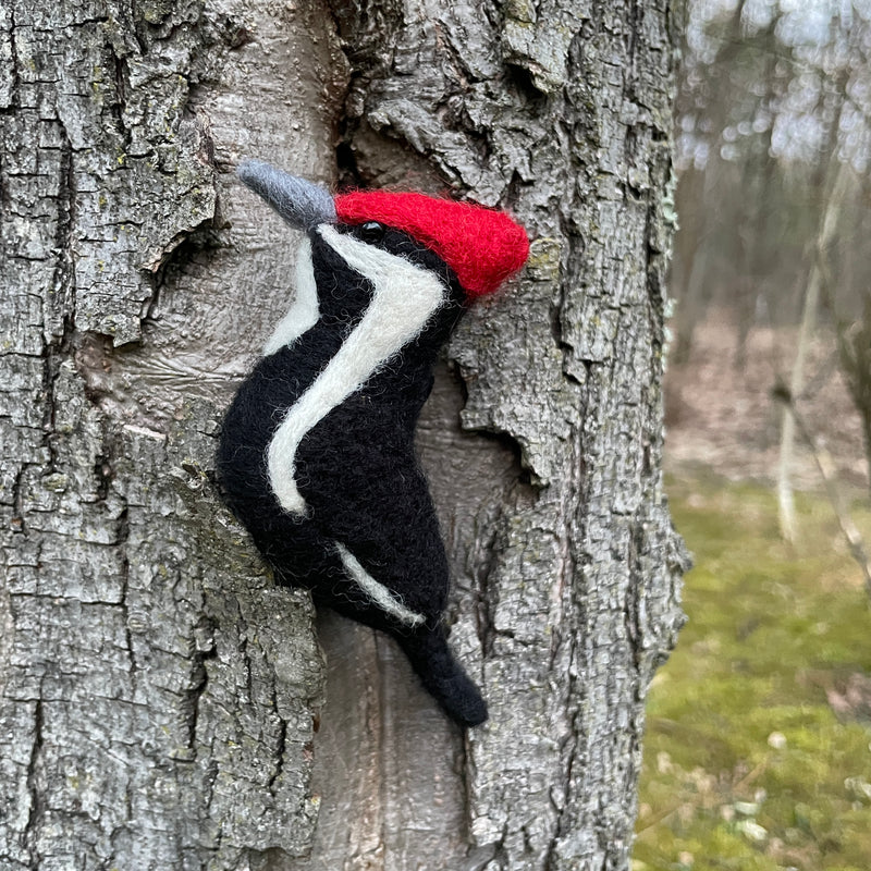 Felted woodpecker ornament against a tree trunk