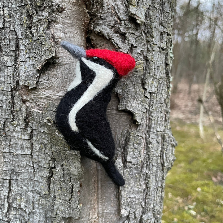 Felted woodpecker ornament against a tree trunk