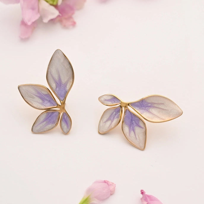 floral-shaped earrings with gold frames and purple accents on a white background with pink flowers.