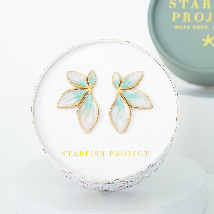 Gold and green earrings on a white stand with 'Starfish Project' branding.