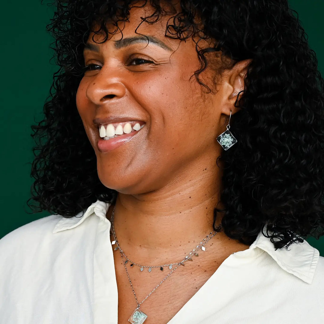 Woman wearing earrings and a necklace against a green background