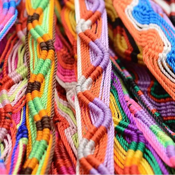 A close-up of colorful friendship bracelets made of acrylic, featuring various patterns and designs.