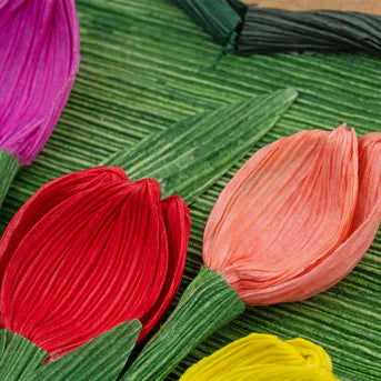 Colorful cornhusk flowers on a textured green surface