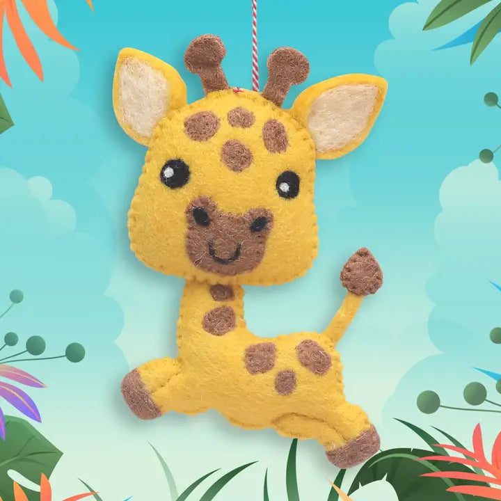 A yellow felt giraffe ornament with brown spots, hanging by a red-and-white string against a colorful tropical background.