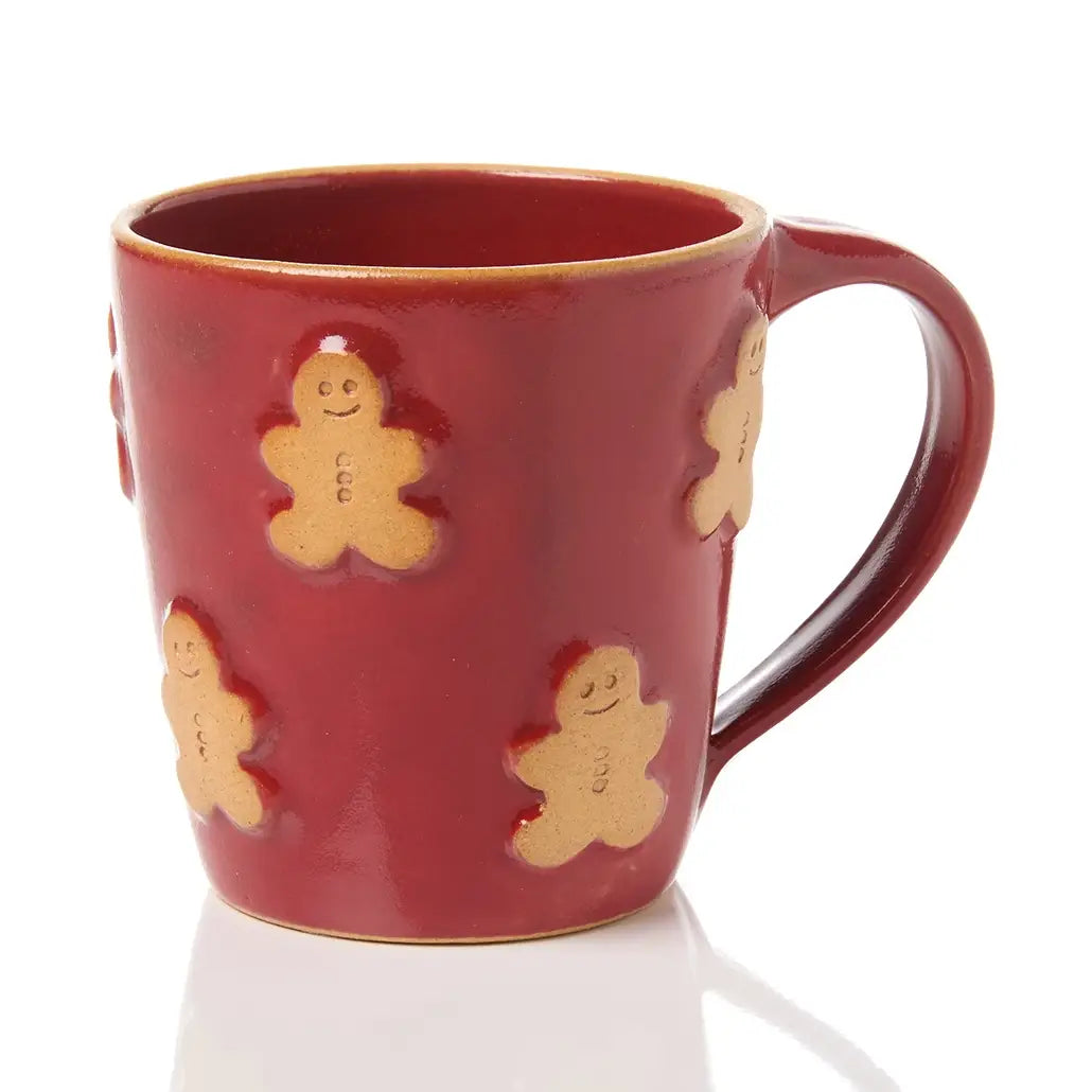 A glossy red ceramic mug decorated with raised gingerbread men figures, shown on a clean white background with a soft reflection.