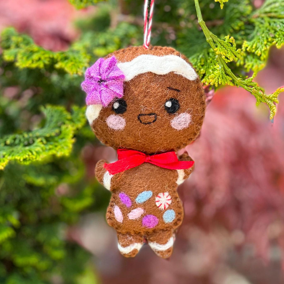 Gingerbread girl ornament with a flower on a Christmas tree