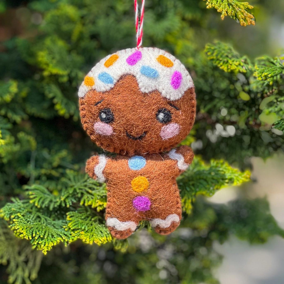 Gingerbread man ornament with colorful icing on a green tree branch