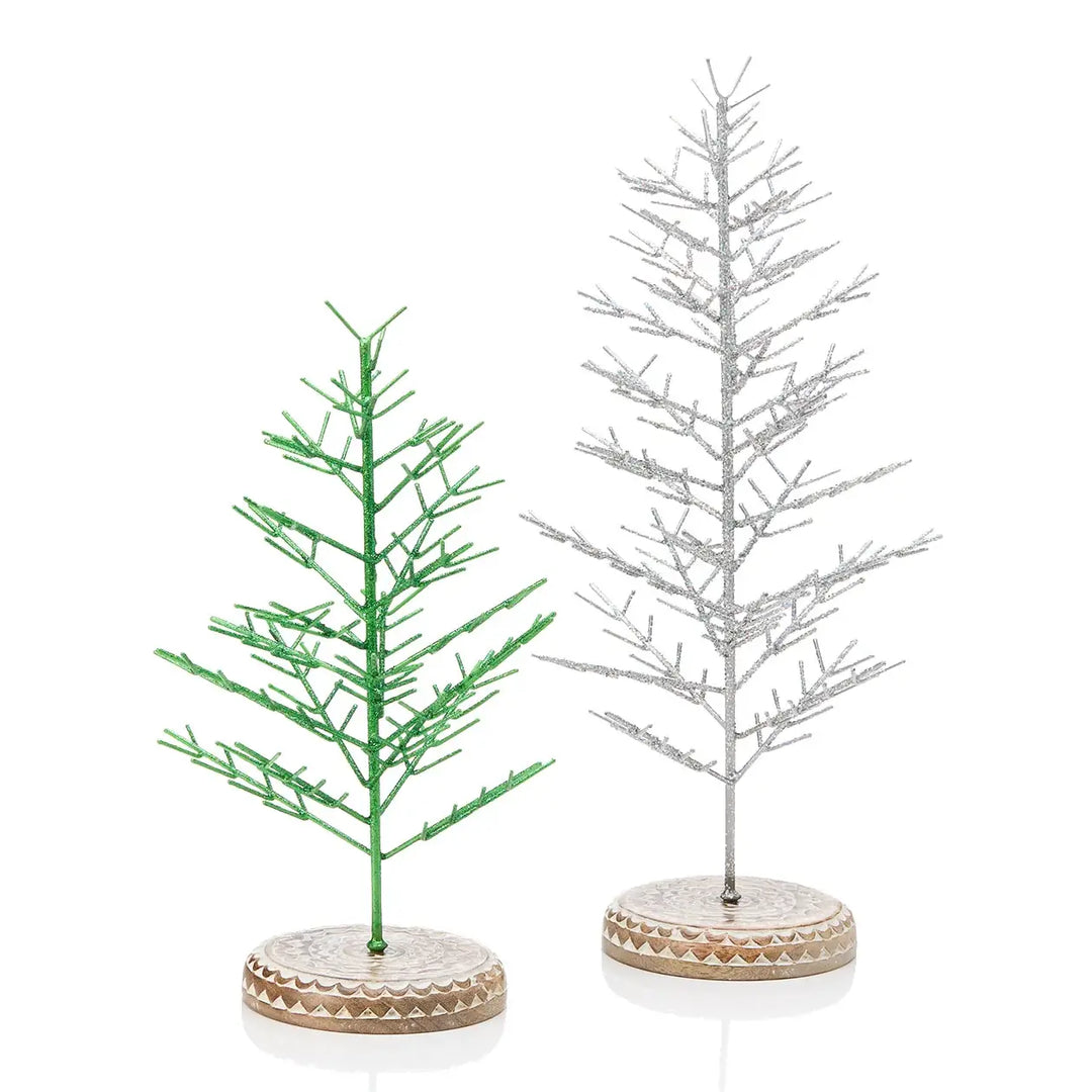 Two miniature decorative Christmas trees on round bases, one green and one silver, shown on a clean white background.