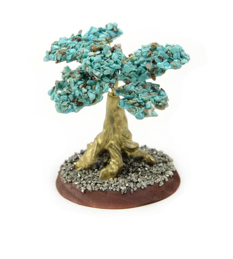A decorative stone tree with turquoise placed on circular wooden base.