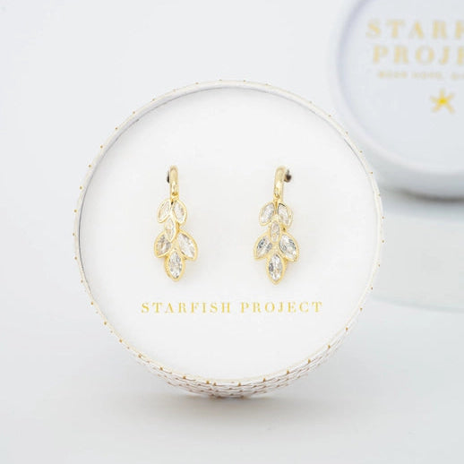 Gold earrings in a Starfish Project box on a white background