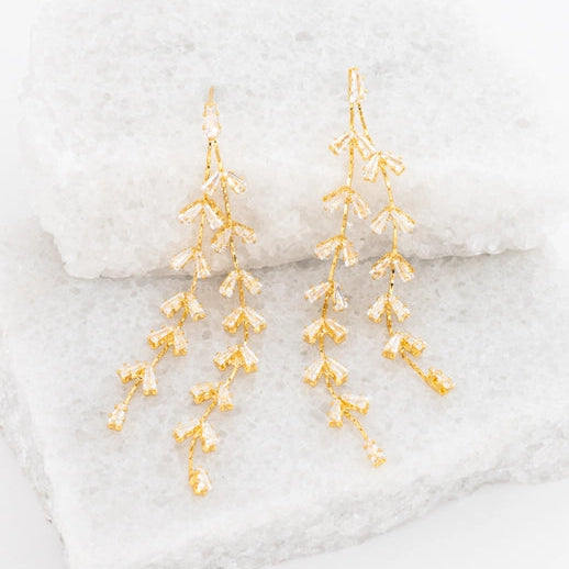 Gold dangle earrings on a marble surface