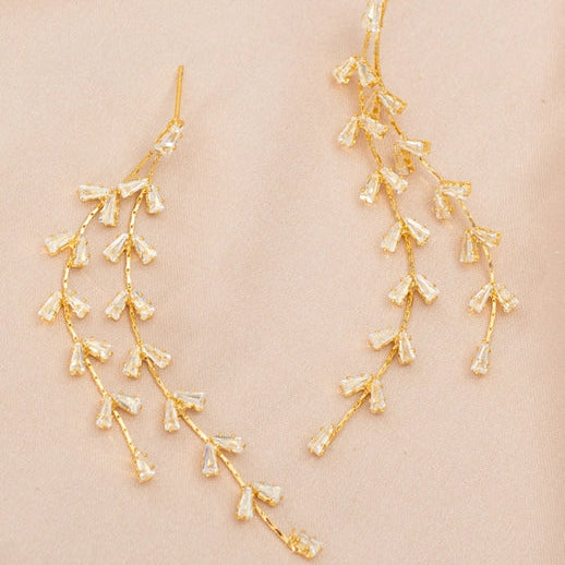 Gold floral earrings on a beige background