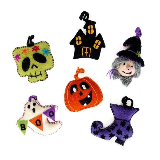 A collection of handmade Halloween ornaments including a witch, ghosts, a pumpkin, and houses with decorative details.