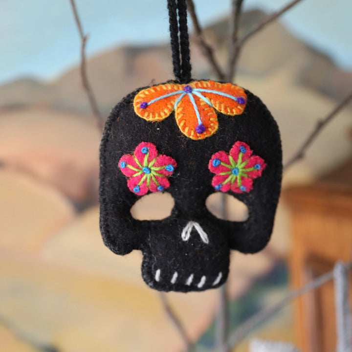 Black skull ornament with colorful flowers and an orange headpiece on a blurred background
