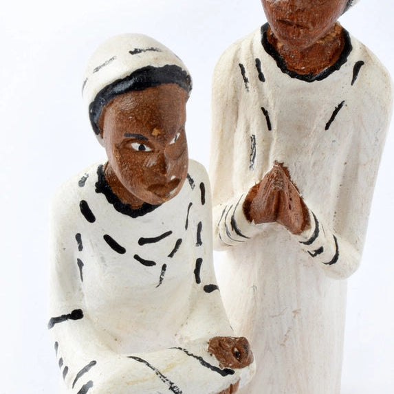 Wooden figurines of two people sitting on a white background