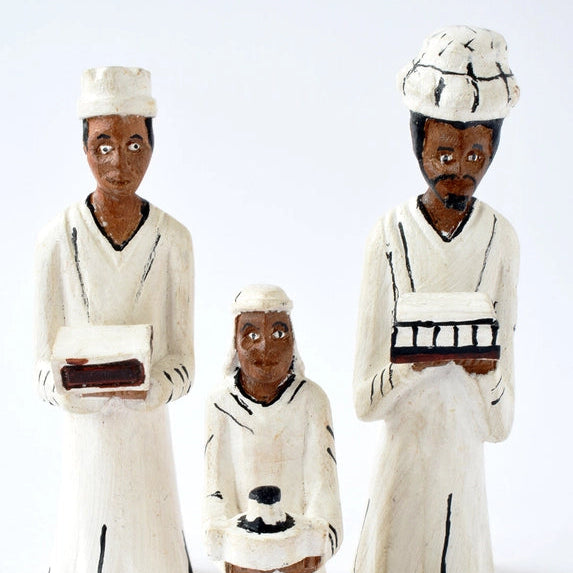 Three figurines in traditional attire on a white background