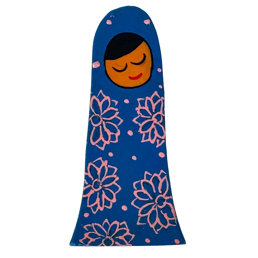 A blue Mary blanket shaped like a doll, featuring a smiling orange face with closed eyes, black hair, and pink floral patterns on a white background.