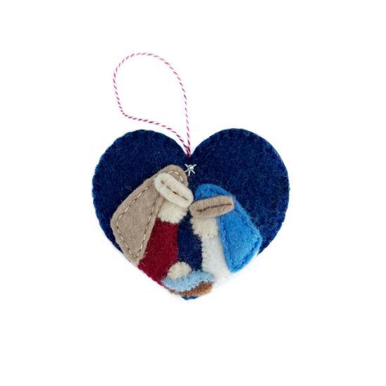 A heart-shaped felt nativity ornament featuring the Holy Family with blue and red colors, with a red hanging ribbon.