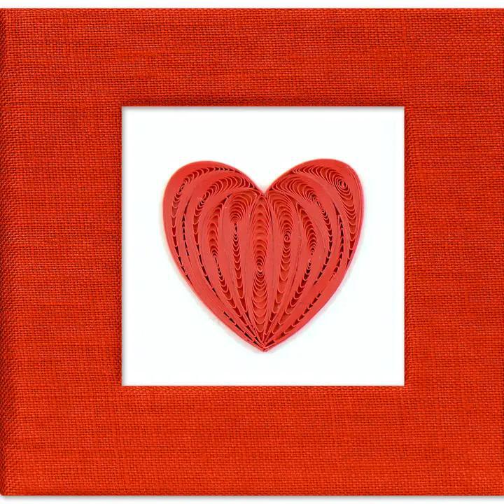 A handcrafted red sticky note cover with a quilled heart design on the front, made of paper, displayed against a white background.