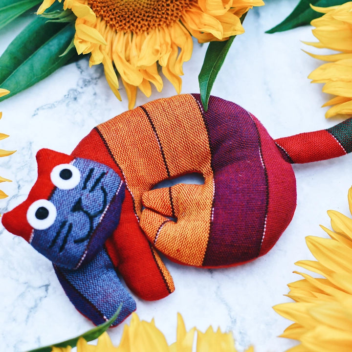 Colorful cat trivet surrounded by sunflowers on a marble surface
