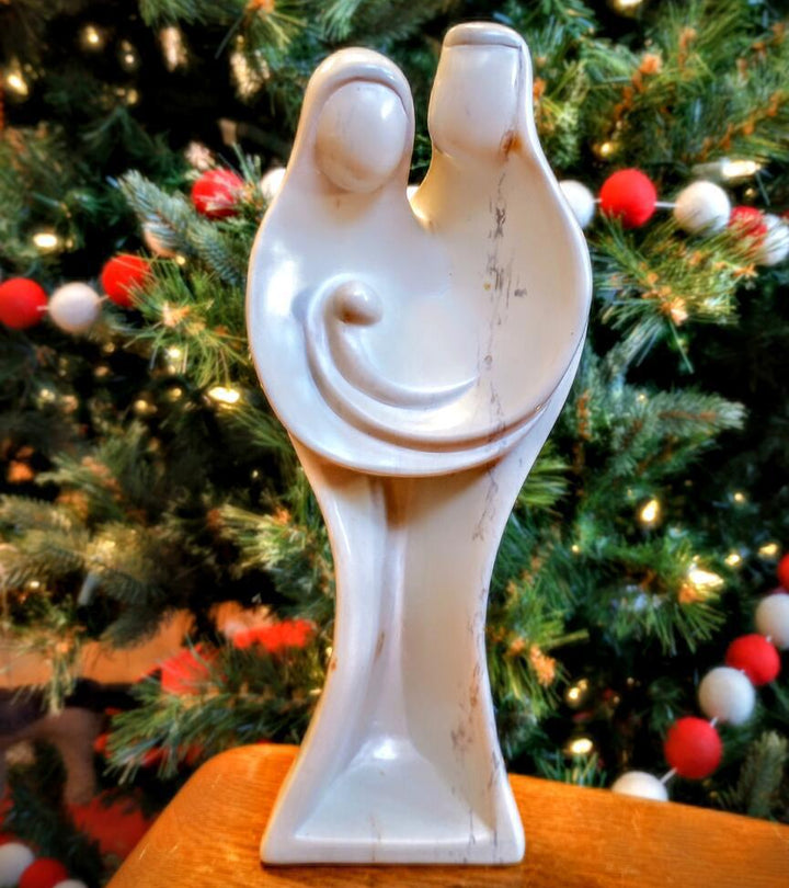 White ceramic nativity figurine against a decorated Christmas tree background
