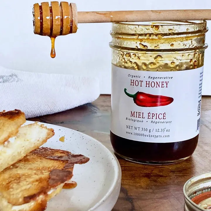 large jar of hot honey with a honey dipper and bread