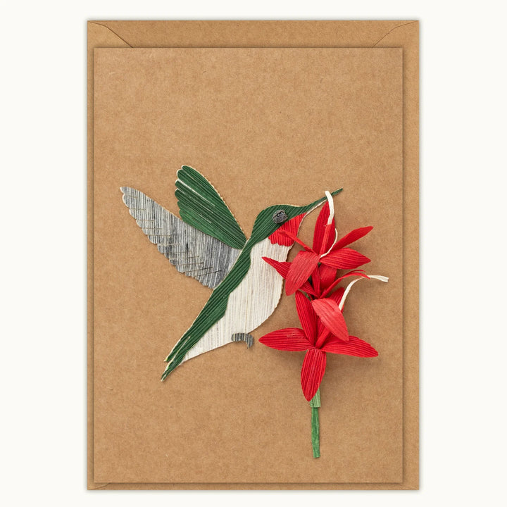 Card with a cutout of a hummingbird and red flowers on a brown background