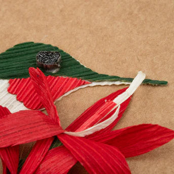Artistic arrangement of red leaves and a green bird on a brown surface